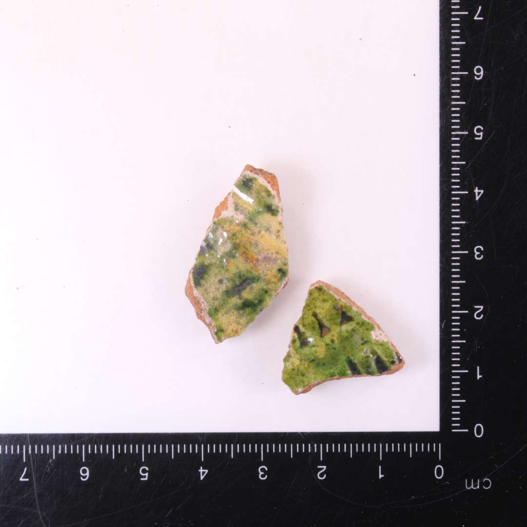 1 sidesk�r med pibelersbegitning og rullestempeldekoration, �   gr�n glasur.�
1 sidesk�r med pibelersbegitning og gr�nsp�ttet glasur.