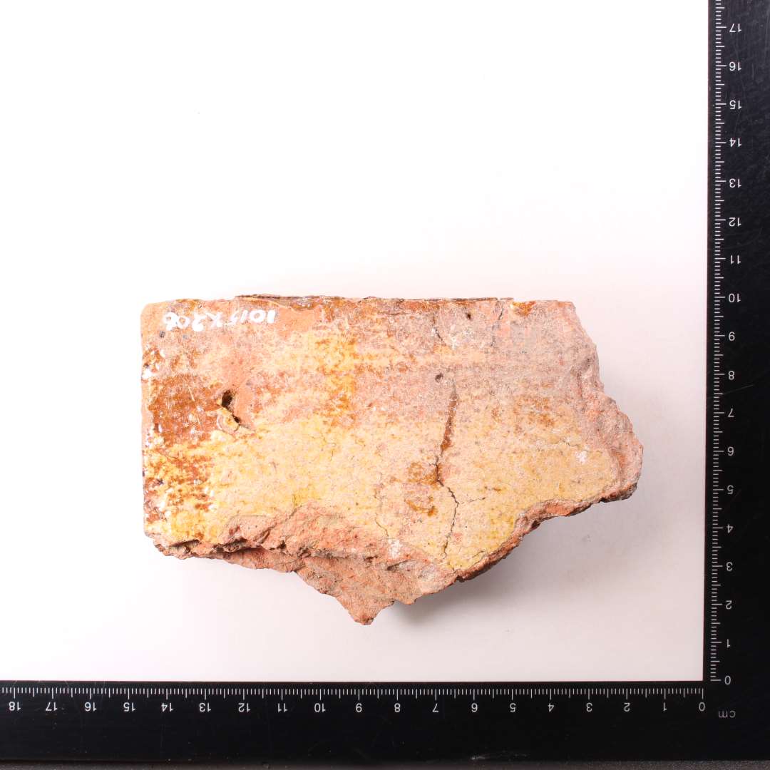 Fragment af kvadratisk gulvflise. Pibelersdekoration under glasurlag. Tykkelse: 2,8 cm.