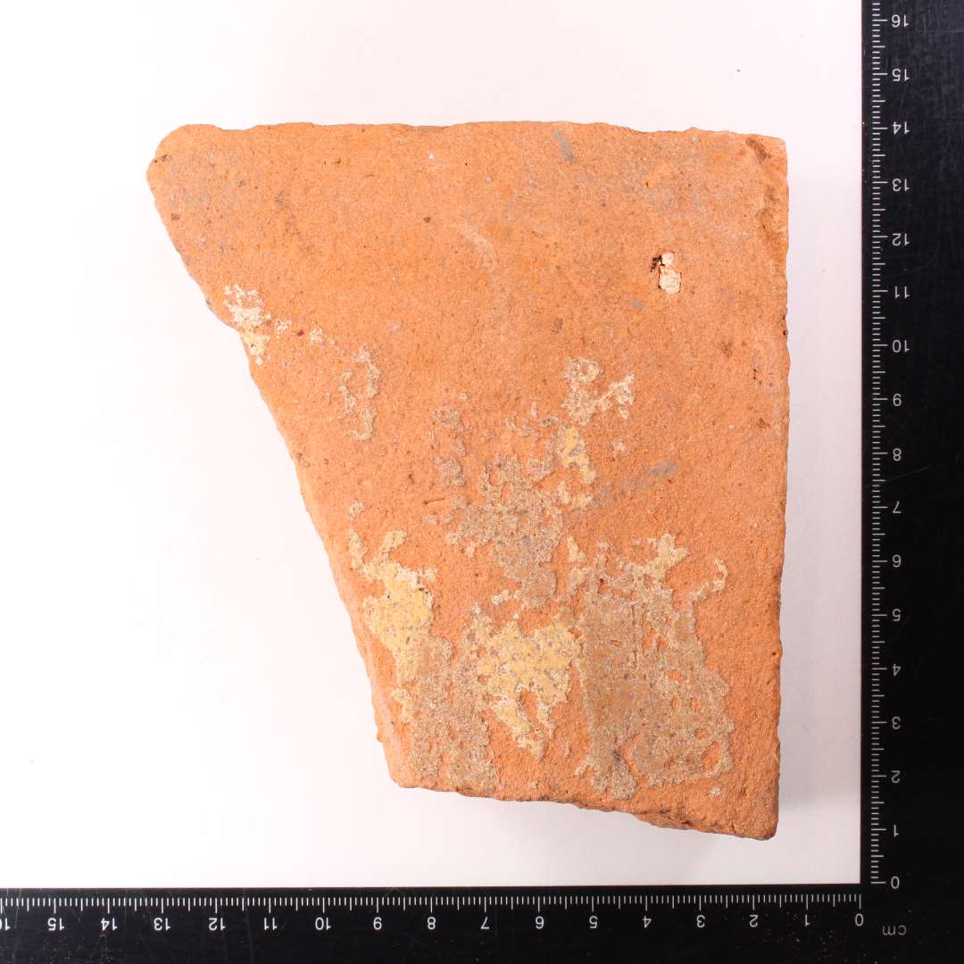 Fragmenteret, kvadratisk gulvflise. Pibelerslag under glaur. Tykkelse: 2,5 cm.