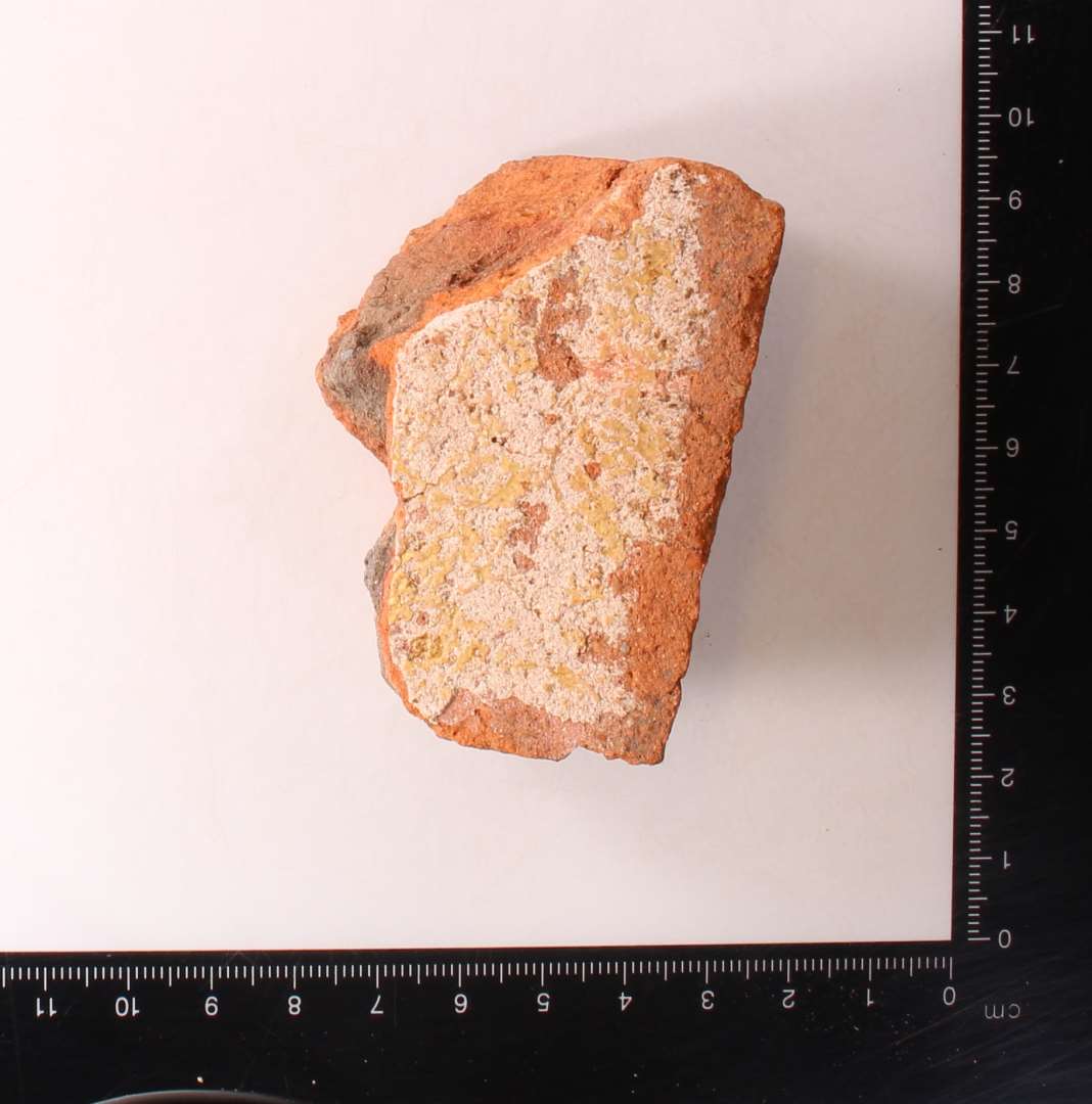 Fragmenteret, kvadratisk gulvflise. Pibelerslag under glasur. tykkelse: 2,5 cm.