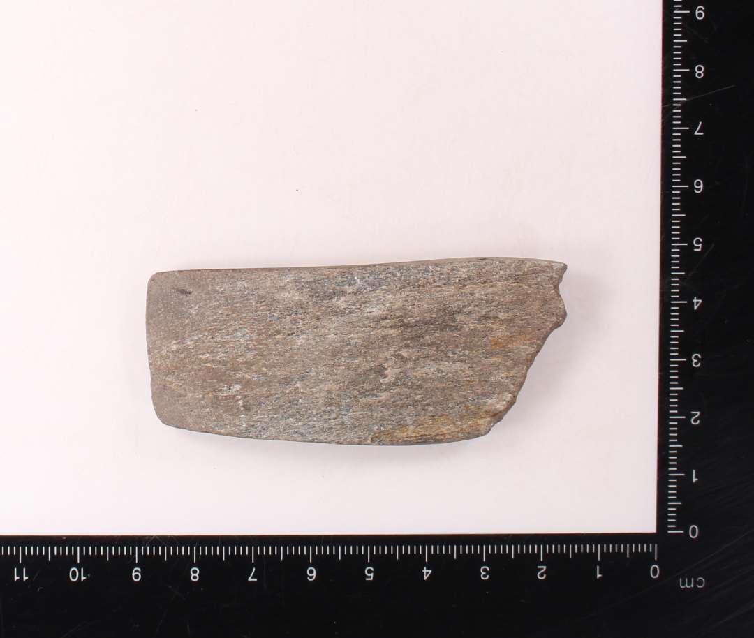 Fragment af kileformet hv�ssesten. Meget tyndslidt