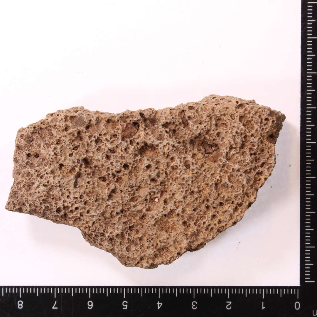 Fragment af kv�rnsten af basalt. Kraftigt slidt fragment, max.� tykkelse ca. 1,8 cm.