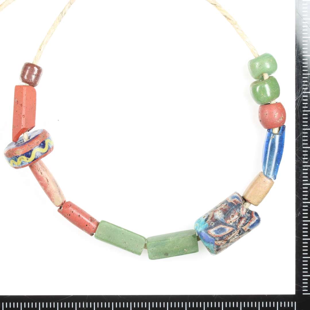 Cylindrisk, Hel, Ugennemsigtig, Brun. R�de strejf i glasmassen.

Alle x017 er fundet samlet i resterne af en formodet pung. Foto af alle samlet, kun p� denne post.