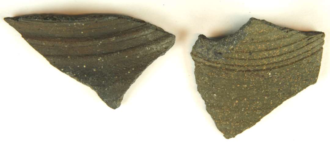 Bugsk�r af gr�brunligt, grynet stent�j med henholdsvis t�ttere og bredere furer og vulster p� halspartiet.