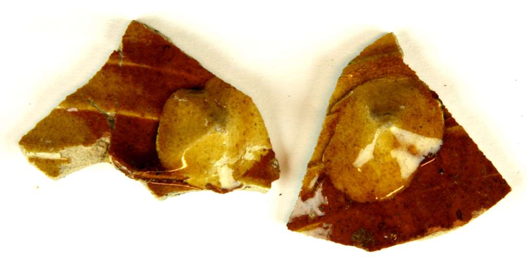 Tre bugsk�r af gr�gulligt, por�st, pibelersagtigt gods fra tyndv�gget kar med svage, omkringl�bende vulstrygge p� ydersiden, der er forsynet med pletvis begitning af r�dlersmasse, hvorover der er lagt brede flade pigknoppe (en p� hvert sk�r) af pibelersmasse. Hele ydersiden er d�kket af klar blyglasur.