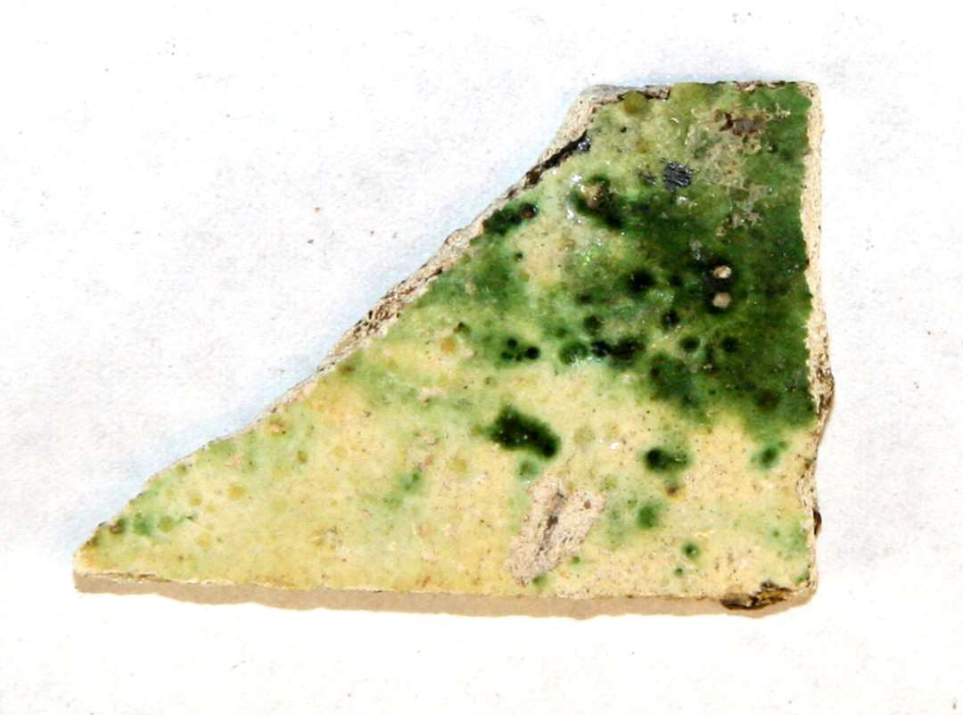 1 sidesk�r af lysegr�t, pibelersagtigt, por�st gods, hvis yderside er d�kket af uj�vn, gr�nligsp�ttet blyglasur.