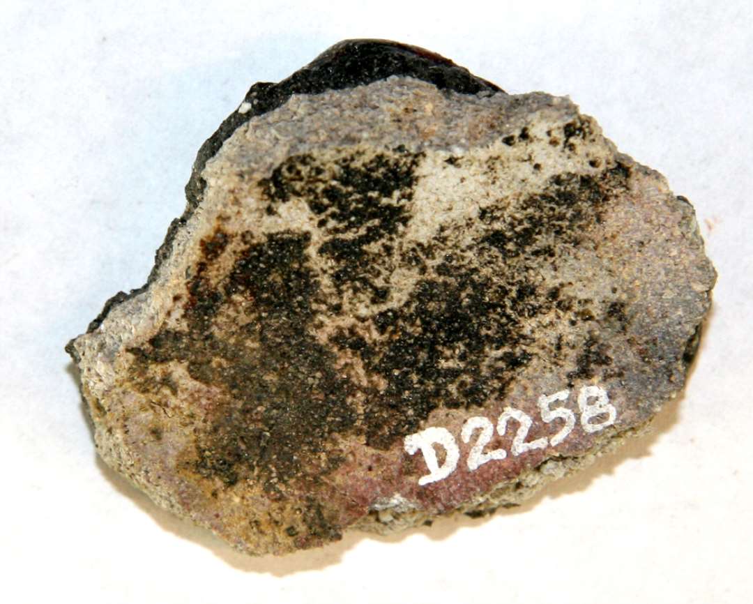 1 sidesk�r fra smeltedigel af gr�ligt, por�st sandblandet gods. Ydersiden er d�kket af en sintret bl�ret skorpe, hvis overflade fremtr�der som et r�dsort, glasuragtigt lag.