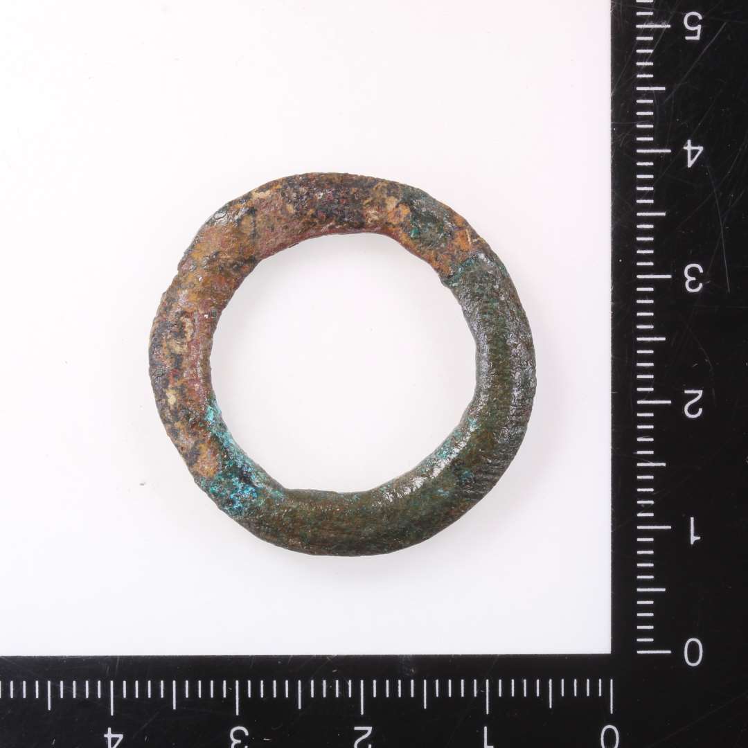  ringsp�nde. Kons.��Bronzering, � 3 cm dannet af en 4 mm bred bronzeskinne m. facetteret tv�rsnit. Kan v�re til et ringsp�nde, men mangler indsn�vringen til tornen. 