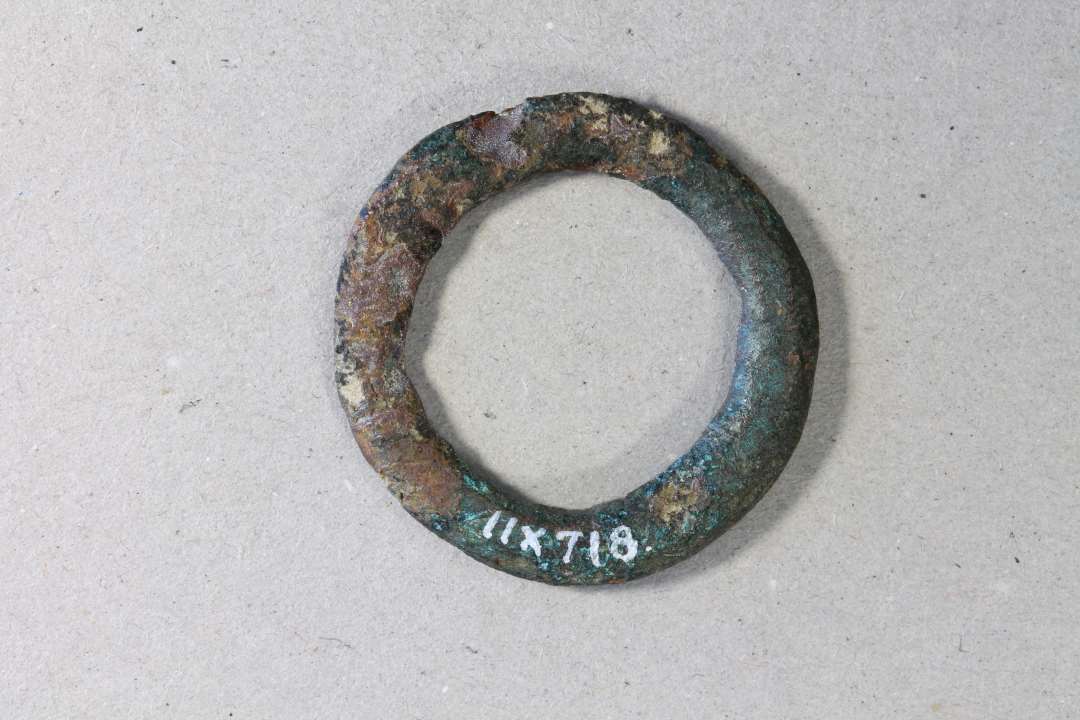  ringsp�nde. Kons.��Bronzering, � 3 cm dannet af en 4 mm bred bronzeskinne m. facetteret tv�rsnit. Kan v�re til et ringsp�nde, men mangler indsn�vringen til tornen. 