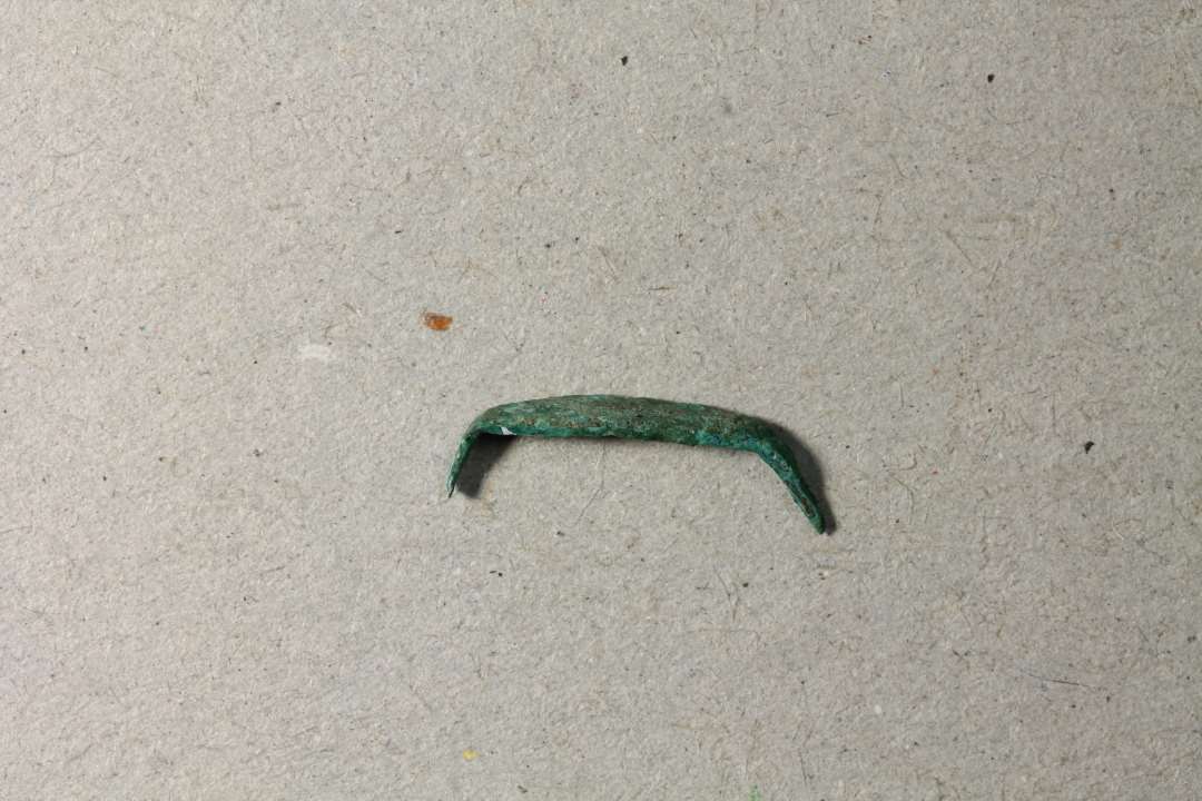 Krampe. Lakeres.��Meget lille pyntebeslag i form af en krampe, l. 1,2 cm