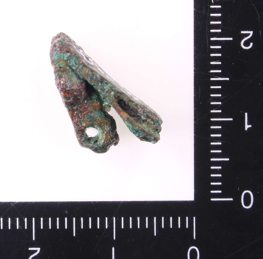 Lille bogbeslag (?) best�ende af to smalle plader, 5 mm brede, og et lille st�bt hoved med �je.