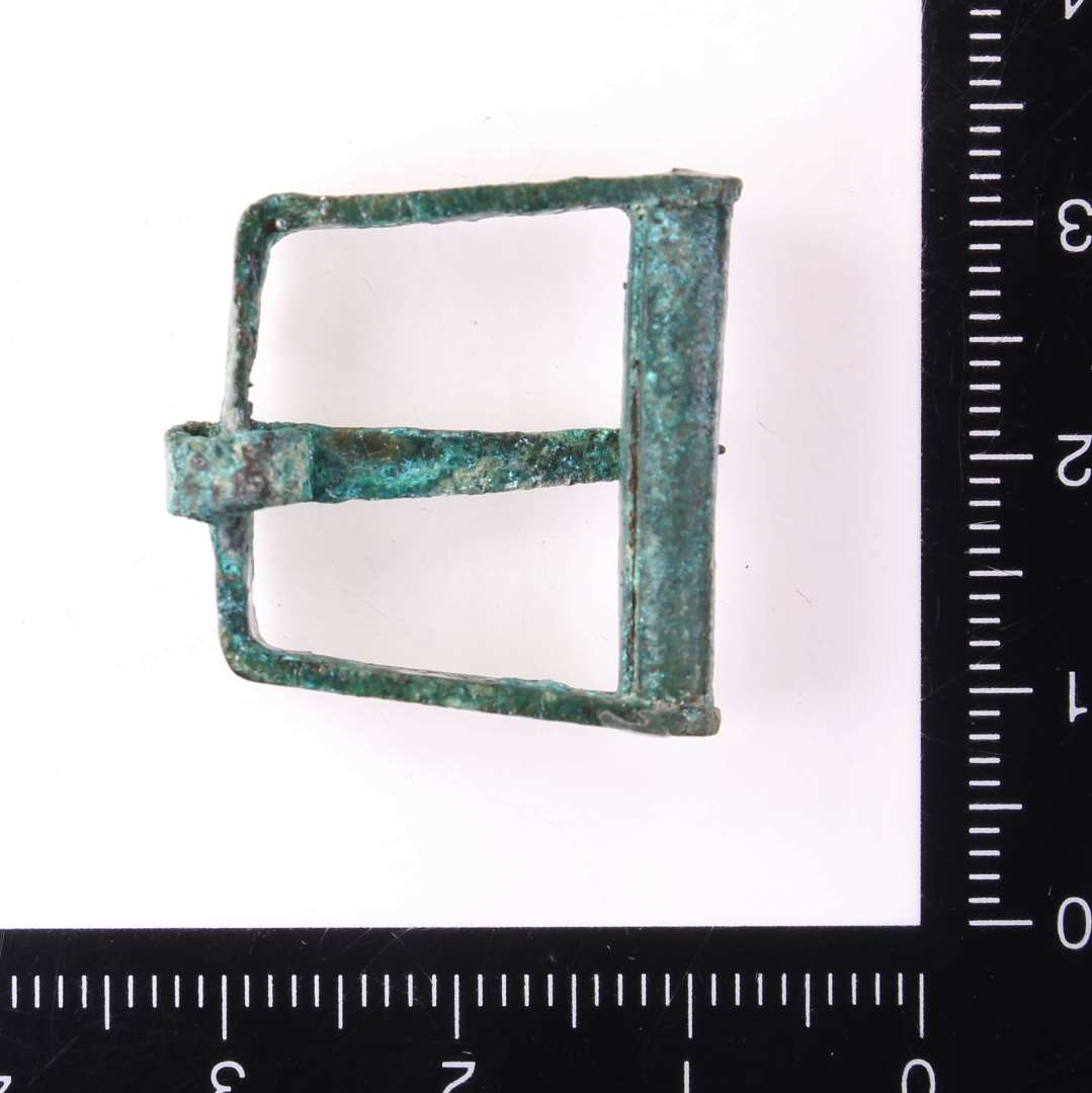 Omtrent kvadratisk sp�nde m. bevaret torn, ikke st�bt, bredde 2,4 cm.