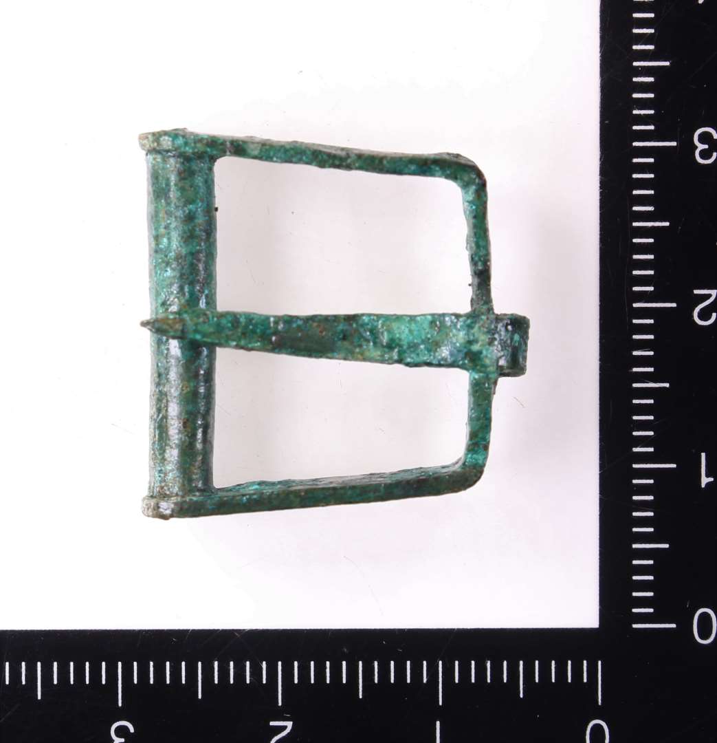 Omtrent kvadratisk sp�nde m. bevaret torn, ikke st�bt, bredde 2,4 cm.