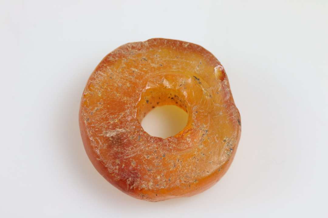 Stor ravperle eller anden genstand. Flad, skiveformet. tykkelse ca. 1 cm, diameter ca. 3 cm