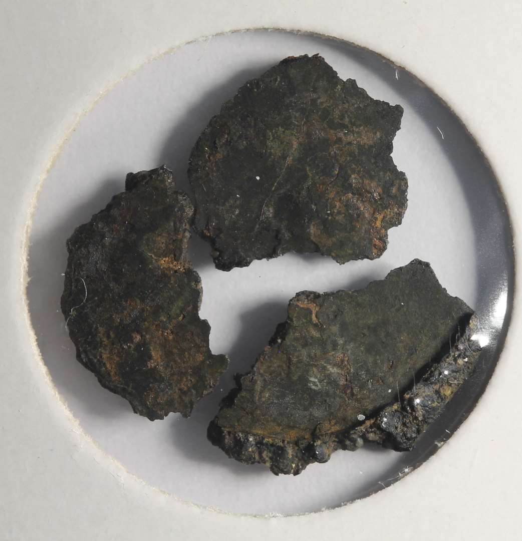 Rx 114: 2 sammenkittede m�nter (m�ntskat!).�Kan p.t. ikke bestemmes. B�r renses (JCM).
Fotos ogs� af korrosionsskaller.
P� den ene m�nt ses stjerne ala MB544 (mfl).

(NM har m�rkv�rdigvis talt m�nterne som fire (146-149). De to af dem er dog korrosionsskaller fra de to egentlige m�nter).

NM 2020:
M�nt, kraftigt korroderet. 