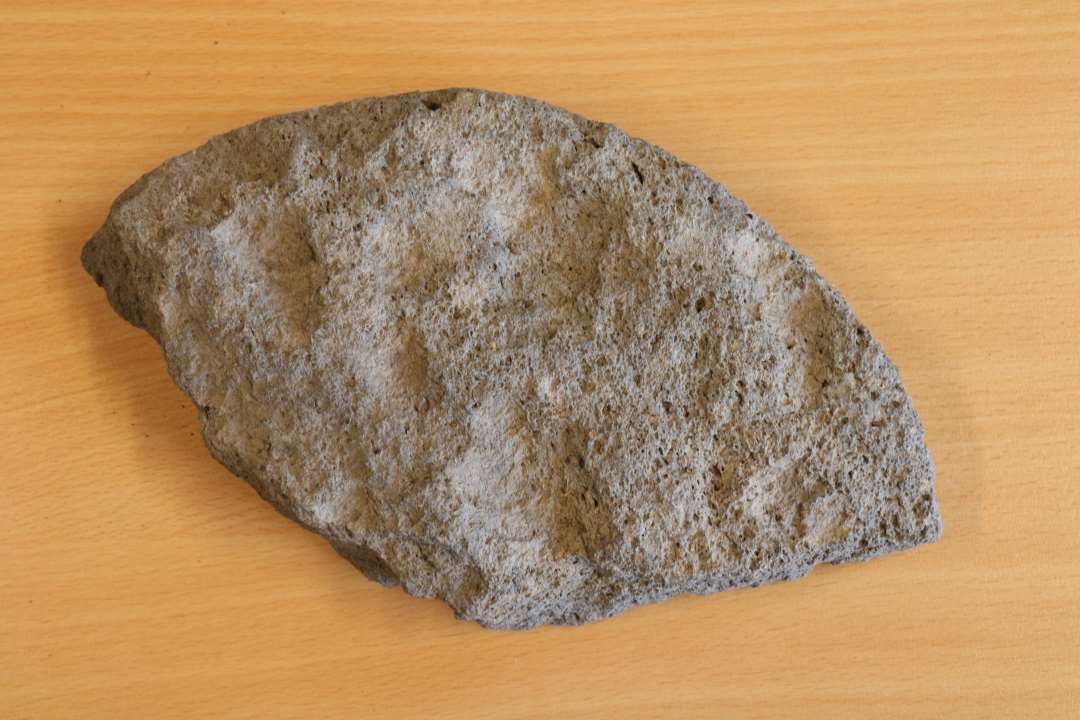 Fragment af lille kv�rnsten, med yderside, meget glat slibeflade, yderrunding og et midterhul. 