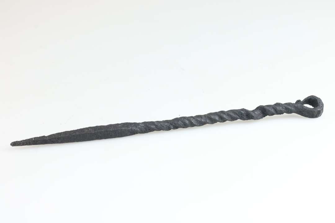 Ca. 16 cm. lang genstand, Den ene ende har firkantet tv�rsnit og ender i en spids,og den anden ende ender i et �je. Halvdelen af skaftet snoet. Konserveret

Lille stegespyd? MIAJ 2024