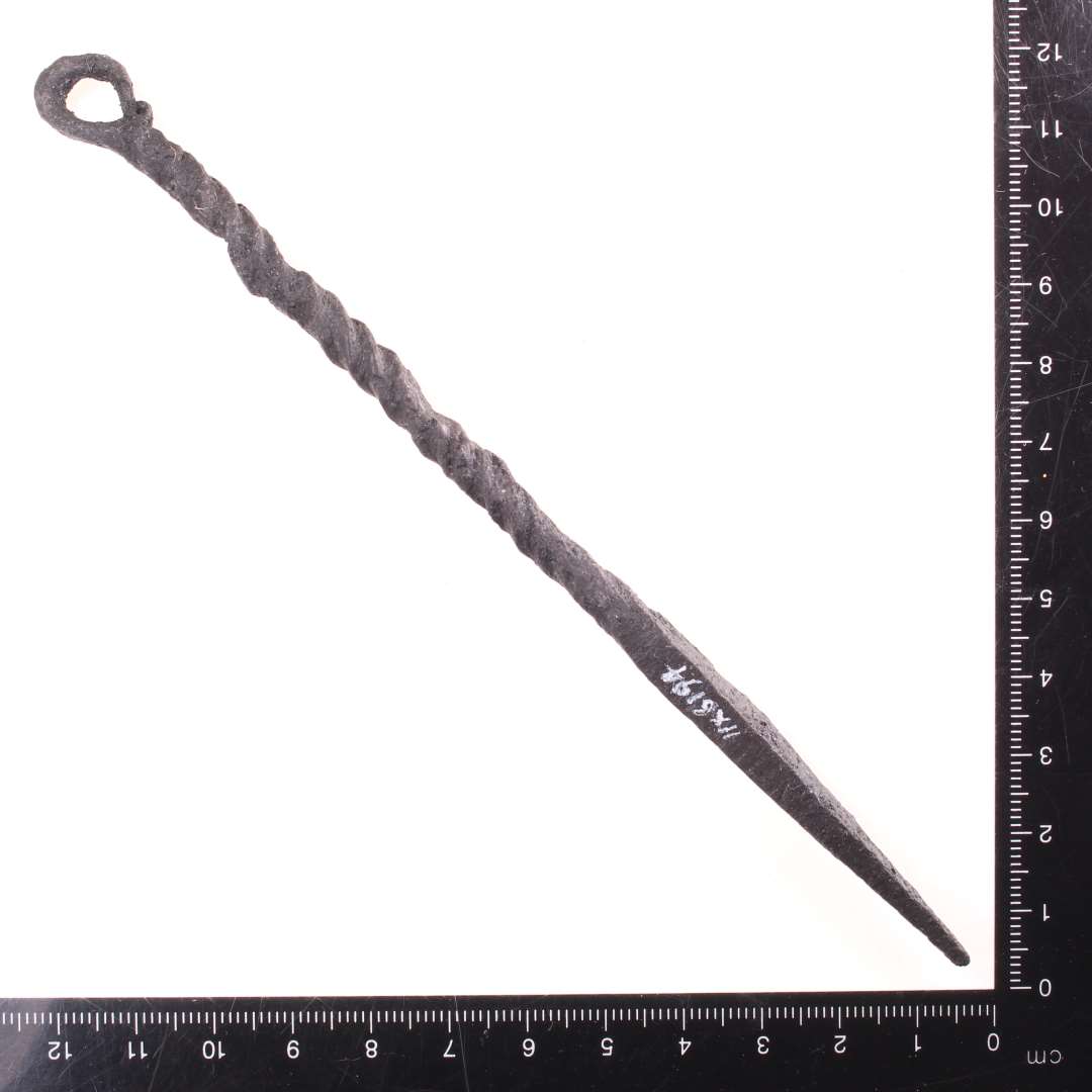 Ca. 16 cm. lang genstand, Den ene ende har firkantet tv�rsnit og ender i en spids,og den anden ende ender i et �je. Halvdelen af skaftet snoet. Konserveret

Lille stegespyd? MIAJ 2024