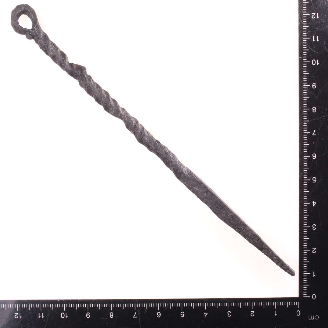 Ca. 16 cm. lang genstand, Den ene ende har firkantet tv�rsnit og ender i en spids,og den anden ende ender i et �je. Halvdelen af skaftet snoet. Konserveret

Lille stegespyd? MIAJ 2024