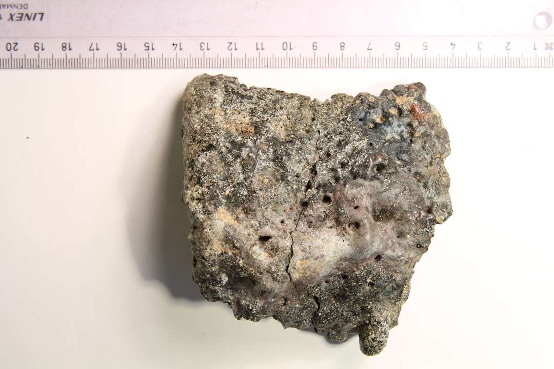 Stort randsk�r (2 sammenh�ngende sk�r) af digel, opr. mundingsdiameter ca. 10 cm. St�rkt sintret ydre, gr�nlig slagge/korrosion indvendig.