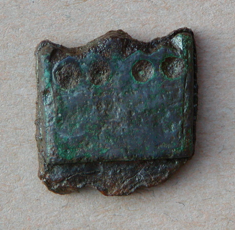 Formodet remendebeslag eller knivbeslag af bronze, monteret p� et underlag af jern. Bronzen m�ler ca. 20 x 16 mm. Sammenlign med x26.