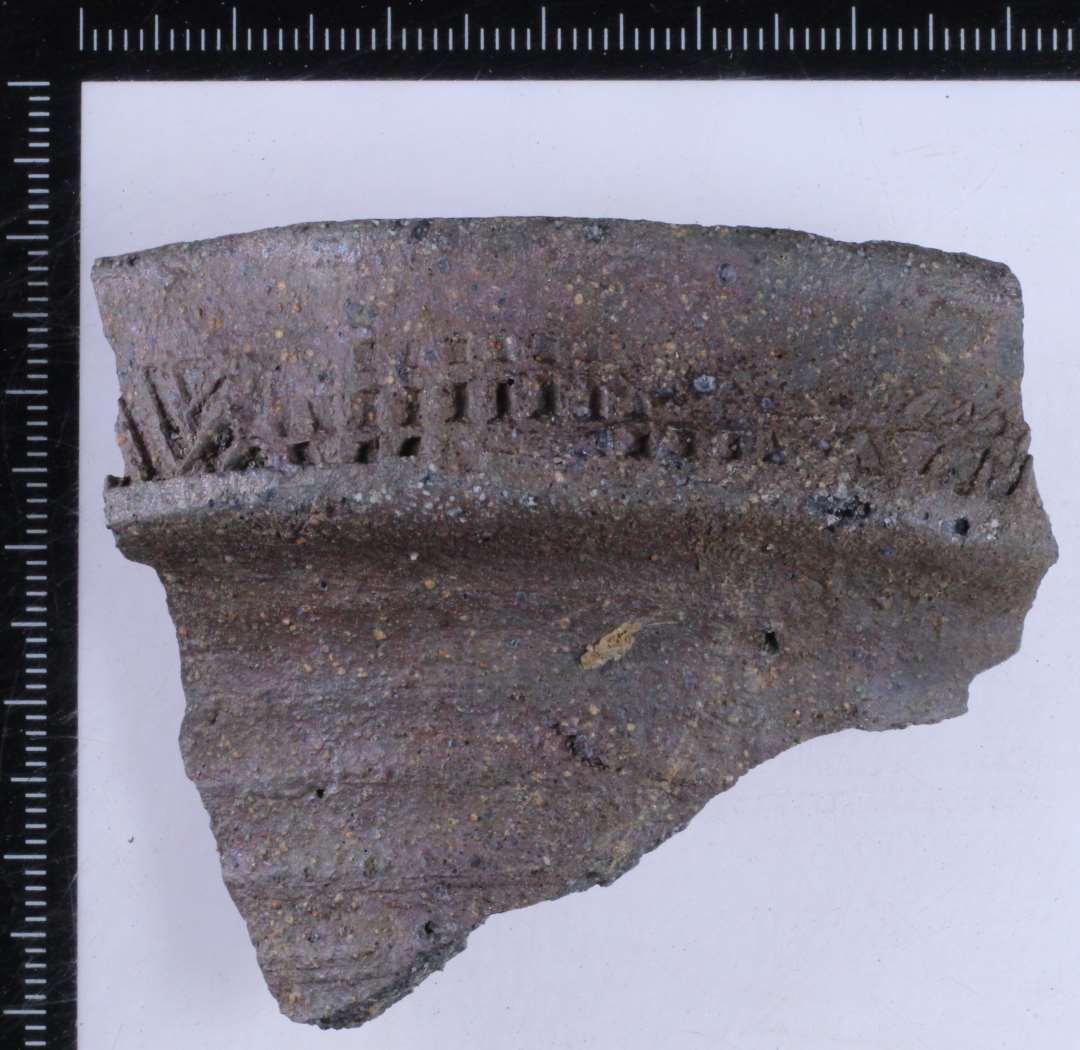 Randsk�r fra n�stenstent�jskande. Oml�bende rullestempling p� randen best�ende skiftevis af tre over hinanden liggende r�kker af rektangler og str� pileformede linjer og trekanter.