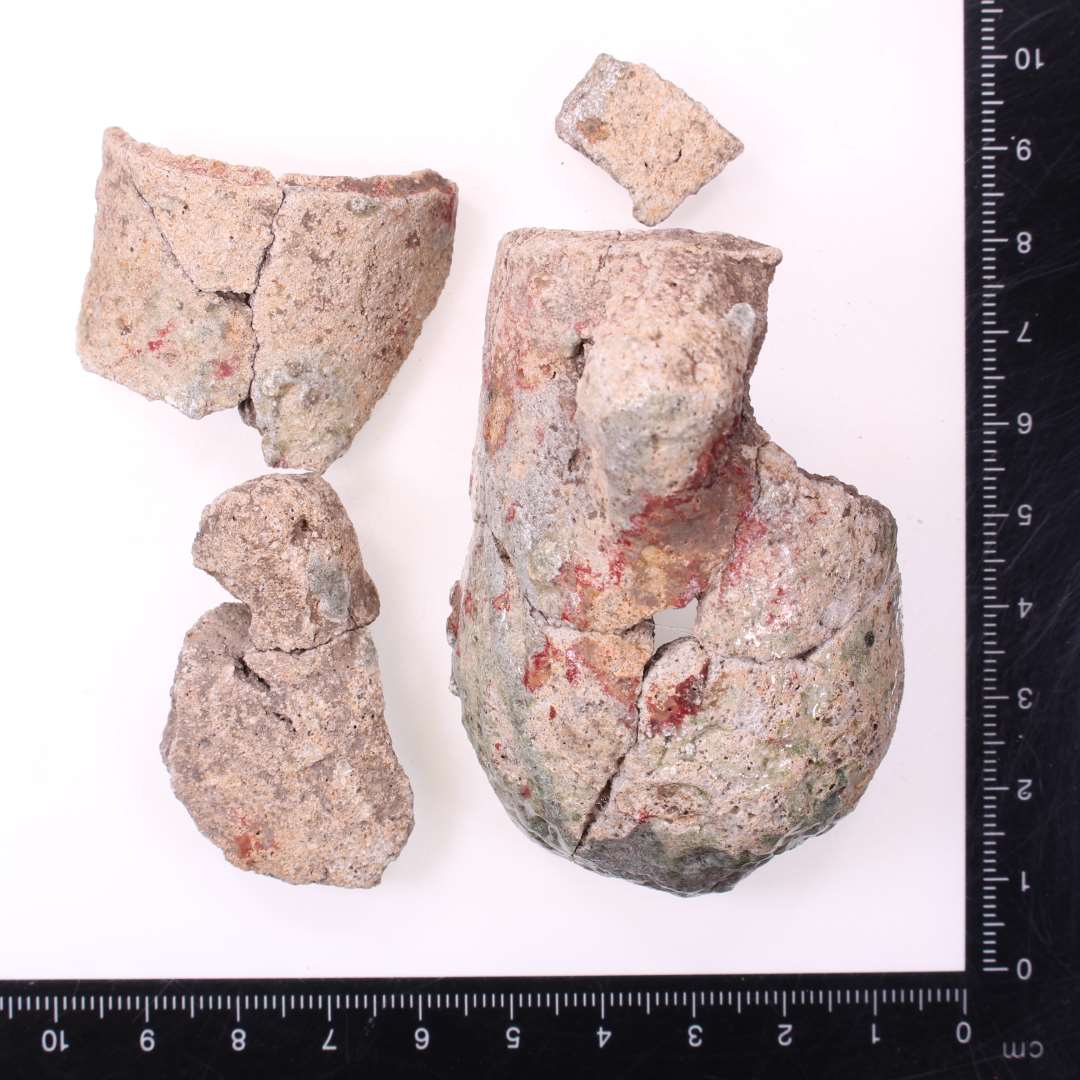 Digelsk�r
Samlet til fire fragmenter af samme digle, bl.a. komplet profil: ca. 7 cm h�j, og 4 cm i diameter. To lodretstillede �rer med vandret hul.