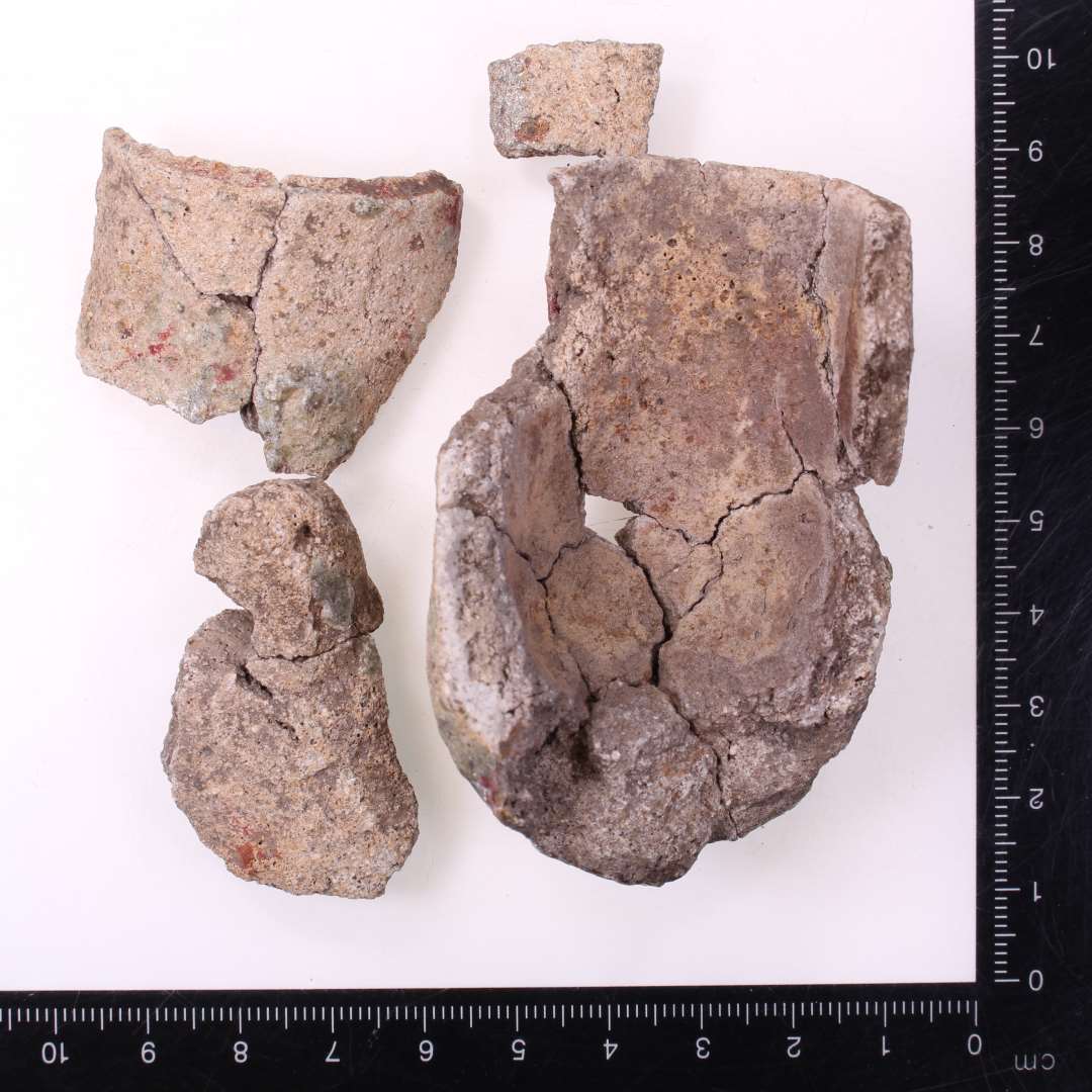 Digelsk�r
Samlet til fire fragmenter af samme digle, bl.a. komplet profil: ca. 7 cm h�j, og 4 cm i diameter. To lodretstillede �rer med vandret hul.