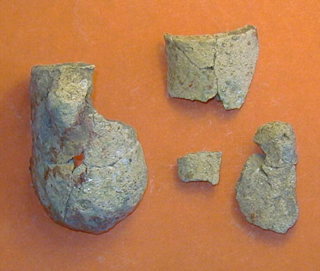 Digelsk�r
Samlet til fire fragmenter af samme digle, bl.a. komplet profil: ca. 7 cm h�j, og 4 cm i diameter. To lodretstillede �rer med vandret hul.