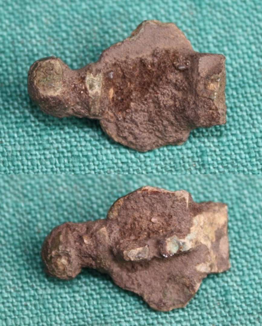 Hovedpladen af korsformet fibel. P� undersiden rester af enkelt n�lef�ste. St�rste m�l: 2,3 cm.