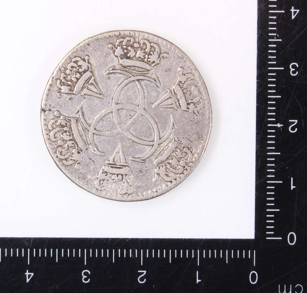 S�lvm�nt
En kopi af en guldm�nt, pr�get i Chr. D V`s tid. 
P� m�ntens forside ses en rytter med en depeche i h�nden. P� bagside er  tre C�r flettet ind i hinanden og i �bningerne i det herved opst�ede m�nster er indflettet romertallet V. Kanten er p� begge side riflet.��
M�ntens diameter 3 cm.�        
Tykkelse 1 mm.��
V�gt: 11,46 g.