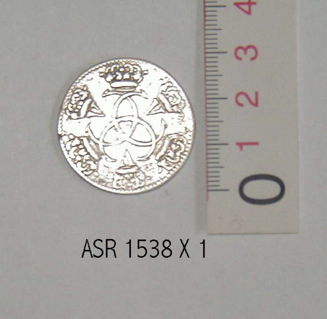 S�lvm�nt
En kopi af en guldm�nt, pr�get i Chr. D V`s tid. 
P� m�ntens forside ses en rytter med en depeche i h�nden. P� bagside er  tre C�r flettet ind i hinanden og i �bningerne i det herved opst�ede m�nster er indflettet romertallet V. Kanten er p� begge side riflet.��
M�ntens diameter 3 cm.�        
Tykkelse 1 mm.��
V�gt: 11,46 g.