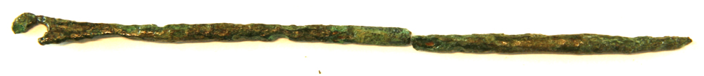 1 st�rkt forvitret bronzen�l af svagt krummet form med fladt udhamret hoved med cirkul�rt �je. N�lespidsen afbrudt.  L: 11,8 cm. 