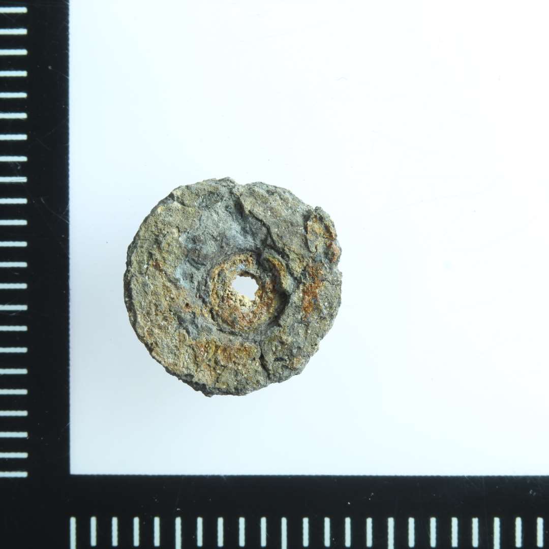 Mindre cirklul�r (9 mm) genstand med hul. Muligvis del af pyntenitte.  