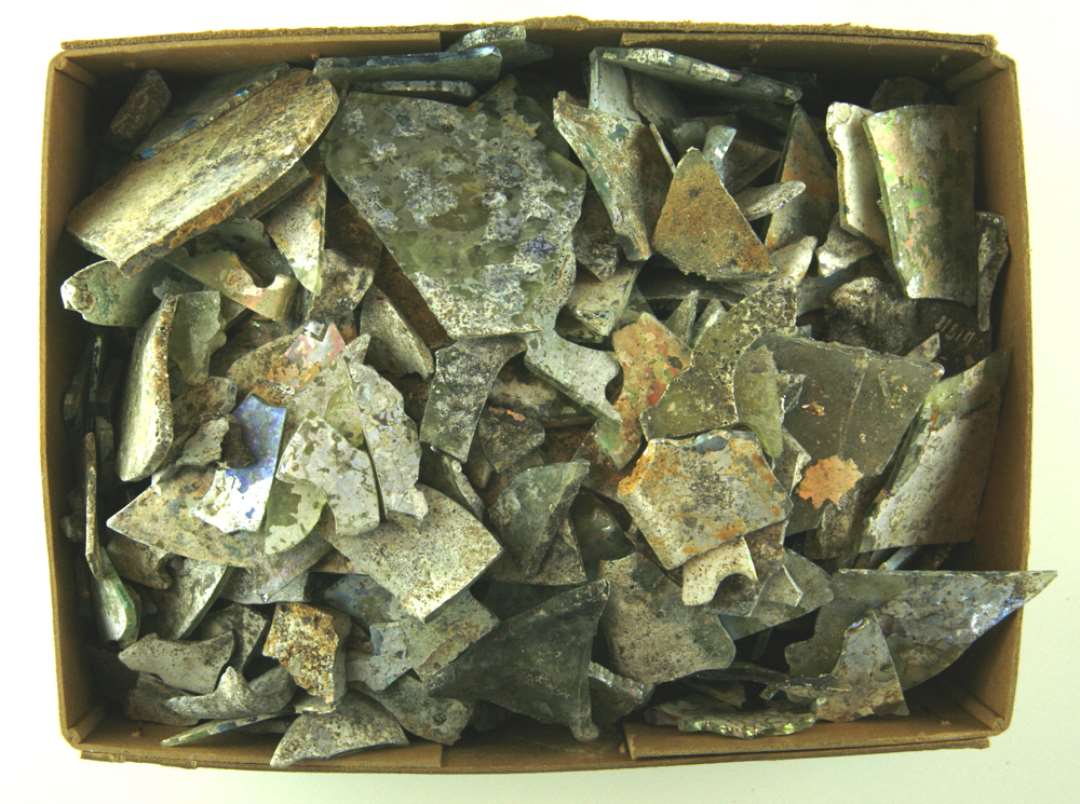 334 sk�r af gr�nne glasruder, der ved brand er blevet ituspr�ngt og st�rk deformeret ved smeltning. Blandt fragmenterne hidr�rer en del fra ruder med rhombeform eller trekantformer.