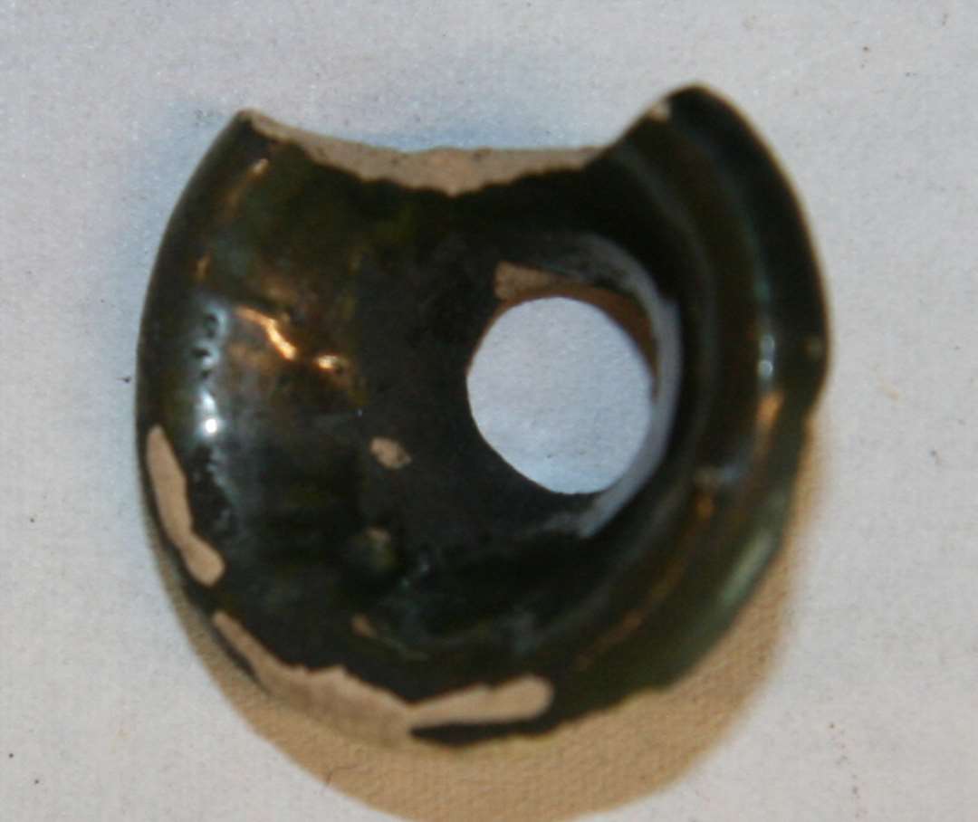 Tragtformet mundingsparti fra miniaturebeholder, salvekrukke, rangle? med indsn�vret hals og glat kraftig udadkr�nget munding. Materialet er gr�gulligt, pibelersagtigt gods, der p� inder- og ydersiden er d�kket af en nu pletvis afskallet s�lvglansagtig blyglasur. Mundingsdiameter: 2,5 cm. Halsdiameter: 1,3 cm.