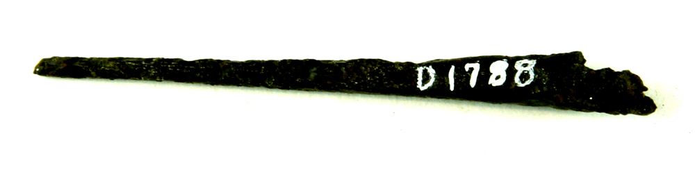 Fragmenteret pilespids af jern, hvis yderste ende er afbrudt. Selve spidsen der er ca. 4,5 cm. lang, har kvadratisk tv�rsnitsform, ca. 3 mm p� hver led. og udvider sig i den modst�ende ende med j�vn overgang til en kr�mmerhusformet st�rkt fort�ret d�lle, ca. 0,9 cm. i st�rste bevaret tv�rm�l. St�rste l�ngde: 7,8 cm.