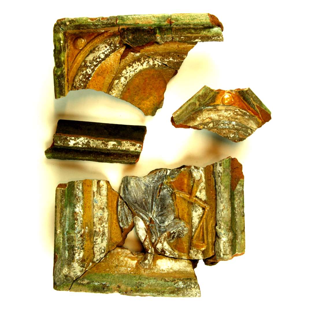 Fragment af polykrom kakkel dekoreret som foreg�ende. Nedre halvdel samt h�jre side sammenlimet af 11 stykker, desuden h�rer D1592 og D1603 sammen hermed. I midten nederdelen af kvindefigur i brun, flagrende kjole, som i venstre h�nd holder en balancev�gt. (Justitia) St�ende i dobbelt s�jlestilling, af hvilke den ydre har baser og dobbeltkapit�ler. Begge stillinger kronet af bueslag. I ydre buesvikkel halvkugle. Ydre, uprofileret ramme, forneden skr�kant. Oprindelig h�jde: 30,2 cm. Oprindelig bredde: 9,0 cm.