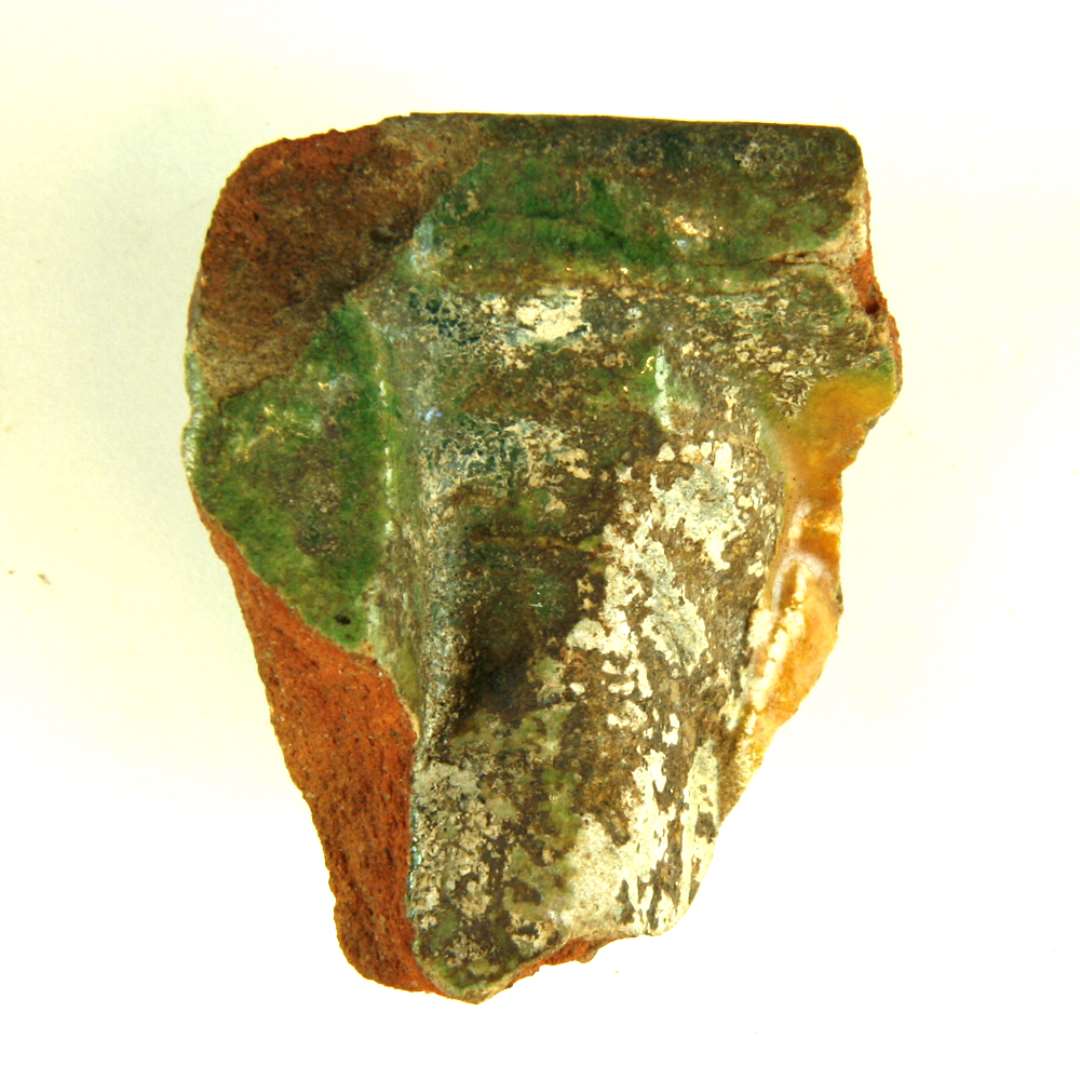 Fragment af kakkel. Nedre h�jre hj�rne med basis og skr�kant og uprofileret yderramme. St�rste m�l: 5 cm.