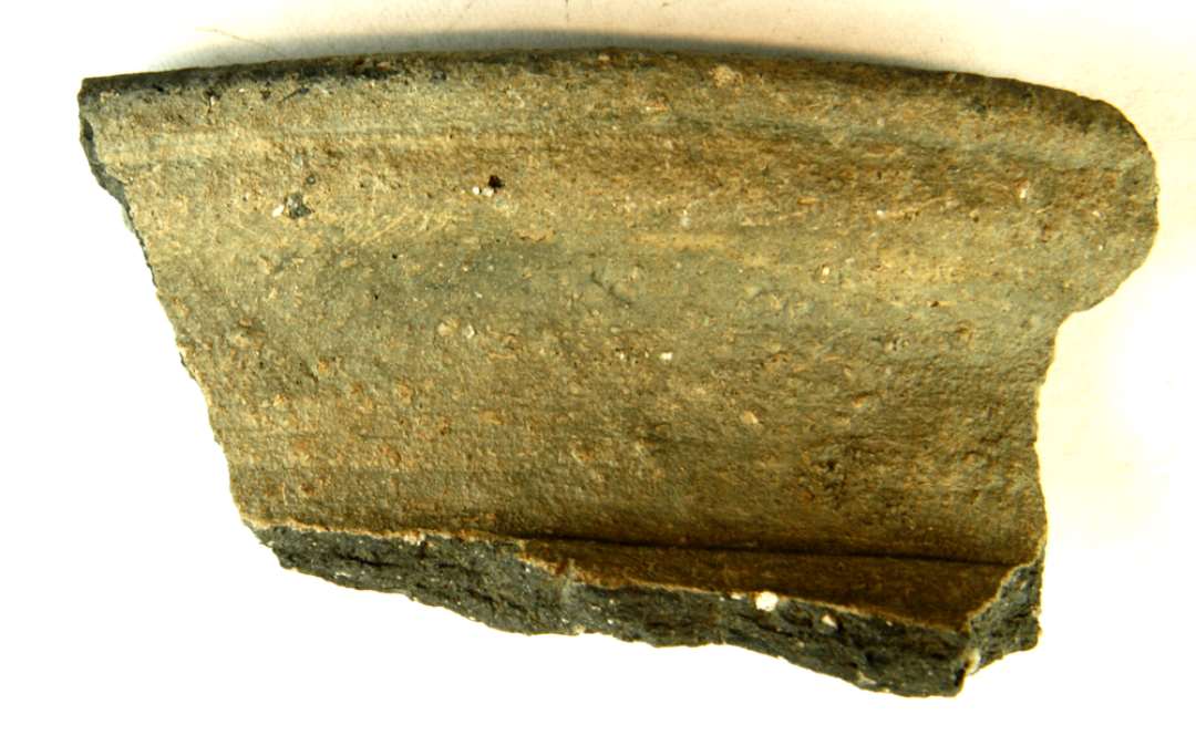 1 mundingsrandsk�r af grovt magret, h�rdtbr�ndt gr� kuglepotte med bred, udludende randkrave, som yderst er k�lleformet profileret.