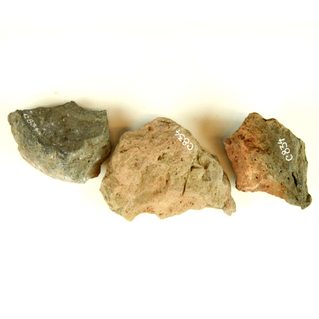 3 v�vev�gtfragmenter af gr�sort og r�dgr�, br�ndt lermasse. 1 fragment har bevaret en stump af midterhullets sidev�g og udviser en    j�vnt, afrundet sidekant, der synes af forts�tte i hv�lvede sider. Diameter: ca. 8 cm. 1 fragment er vandret, spaltet og udviser �n svagt hv�lvet fladeside samt    en stump af midterhullets sidev�g. Diameter: ca. 11-12 cm.