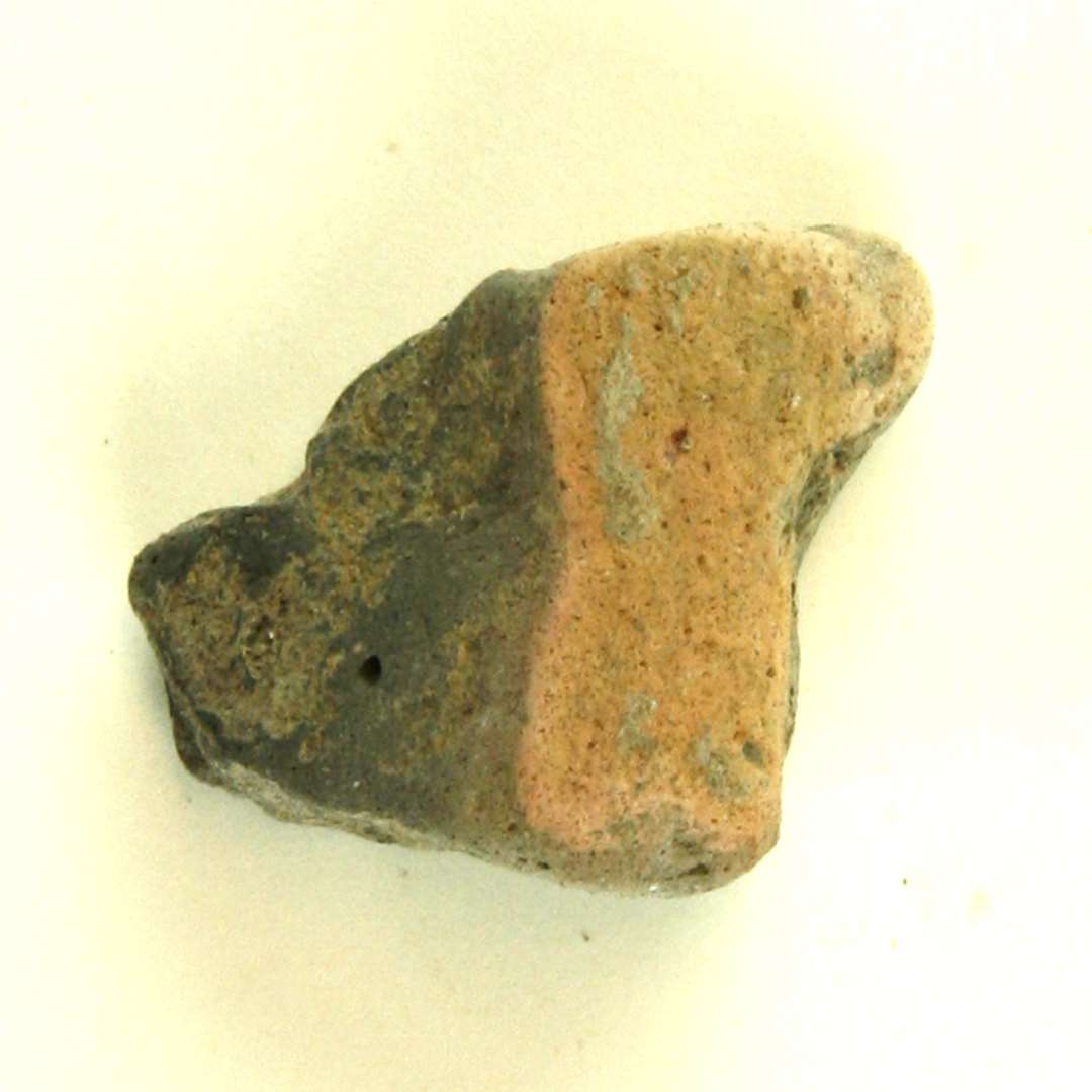 Valn�ddestor fragment af v�vev�gt af br�ndt ler med r�dlig overflade og sort kerne. St�rste m�l: 3,8 cm.