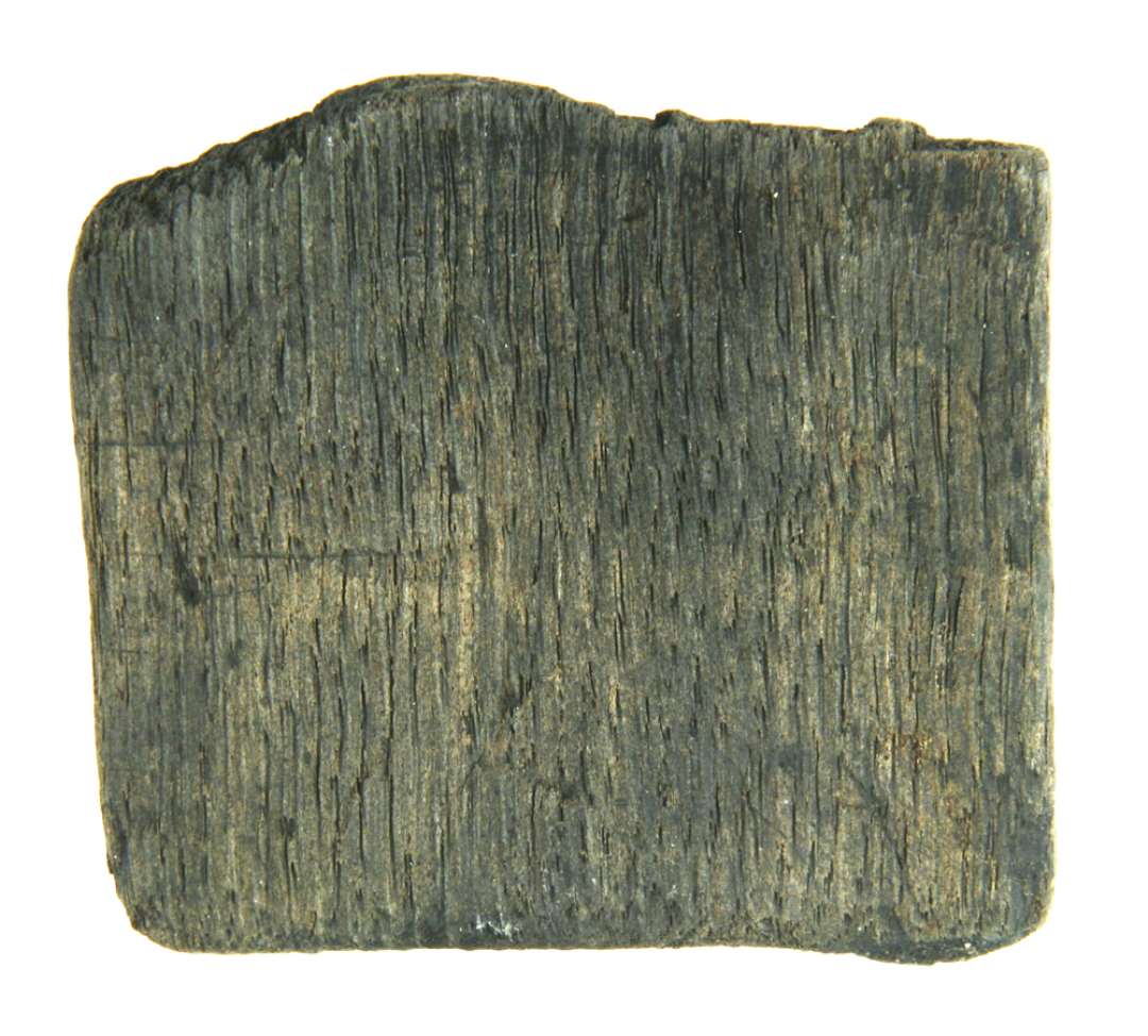 Fragment af karstav. Fra den nedre ende af en egetr�sstav fra kar i b�dker arbejde. Stykket har svag krumning i bredderetningen, den nedre afrundet og ca. 6,5 cm. herfra findes en delvis bevaret ca. 4 mm. bred og ca. 3 mm dyb notrille, hvori karrets bund har v�ret indpasset. Staven er overbrudt i notrillen.  St�rste h�jde (l�ngde): 7 cm. Bredde: 8,2 cm. Tykkelse: 1,5 cm.