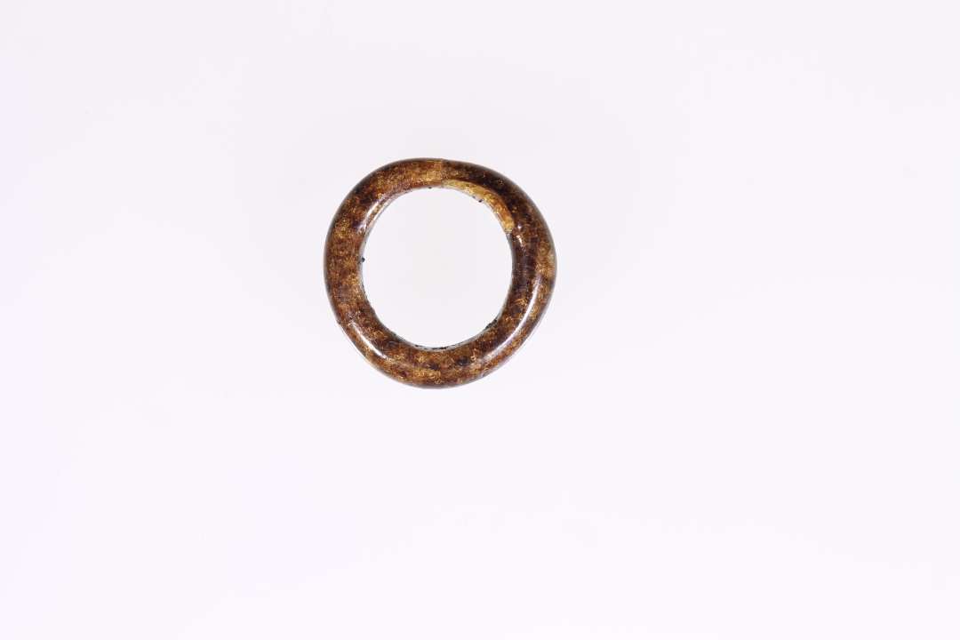 To glasringe. Den ene, sammenlimet af fire stykker, er af nu mat, gr�sort, uigennemsigtigt glas, 1,8-1,85 cm i diam., udf�rt af en ca 0,45 cm tyk p�lseformet glastr�d, der p� ringens sammenf�jningssted kun andrager godt 0,3 cm. Den anden af st�rkt uregelm�ssig cirkelform er af blankt gyldenbrunt nu uigennemsigtigt glas, fra 1,5-1,6 cm i diam. Ringp�lsens tykkelse varierer fra knap 0,3 cm til 0,2 cm p� sammenf�jningsstedet.