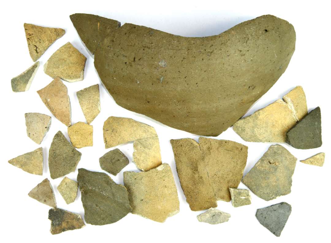 25 bugsk�r af gr�gult, gr�t og gr�brunt, grynet stent�j, flere med svage oml�bende furer p� ydersiden. Flere sk�r sammenlimede af flere stykker.