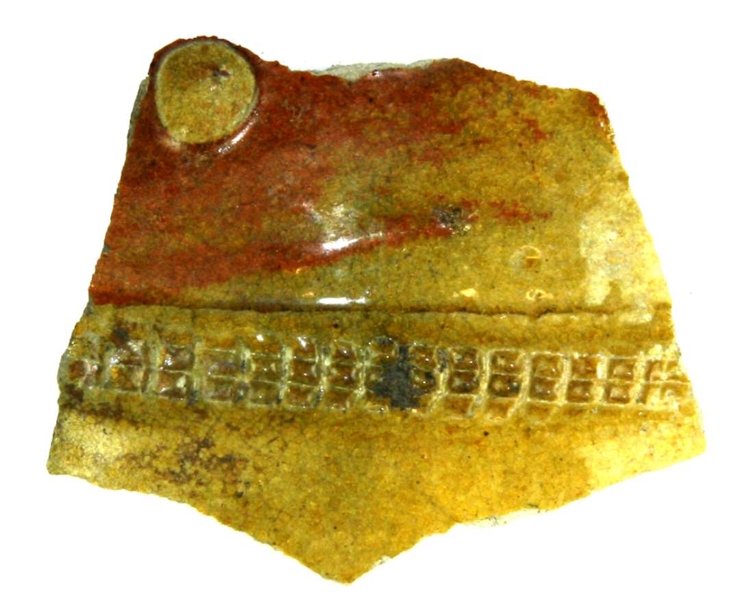 Bugsk�r af gr�lig h�rdtbr�ndt stent�jsagtig lermasse. P� ydersiden p�lagt b�ndvulst med indstemplede forkanter, partiel bel�gning af r�dbr�ndt lermasse, ovenp� hvilken p�lagt knop, i �vrigt klar til let gr�nlig blyglasur p� overfladen.