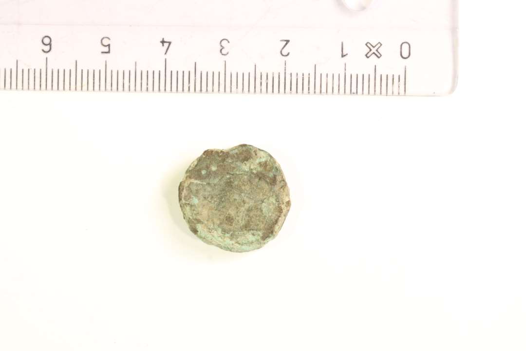 1 skiveformet bronzepatrice ?, 1,8 x 0,4 cm.�Den ene side med markant perle-kant, samten flade d�kket med tre stiliserede fuglehoveder, delvist sammenh�ngende i trekantform.�Datering: YGJ