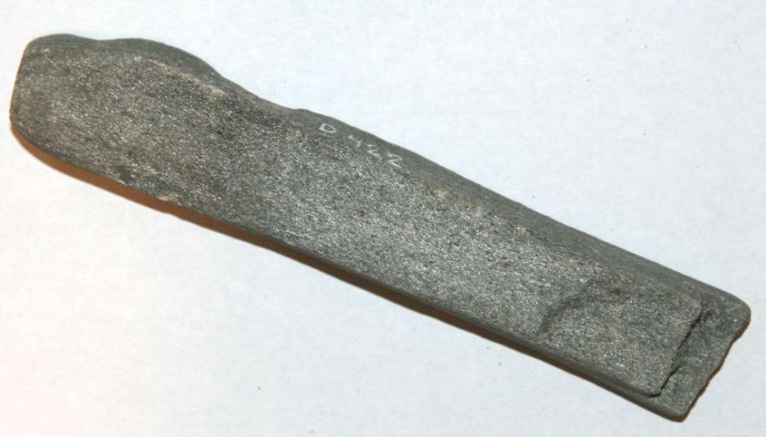 Hv�ssesten. Br�kket i den ene ende. L�ngde: 13,5 cm., bredde: 2,4 cm., tykkelse: 1,7 cm.