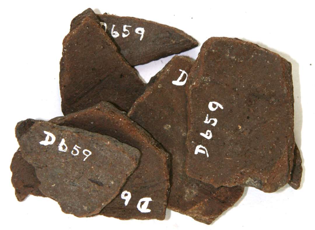 Syv side- og bundsk�r af meget h�rdtbr�ndt lergods. Sort (el. brun) yderside, m�rkebrun sk�v- og inderside.