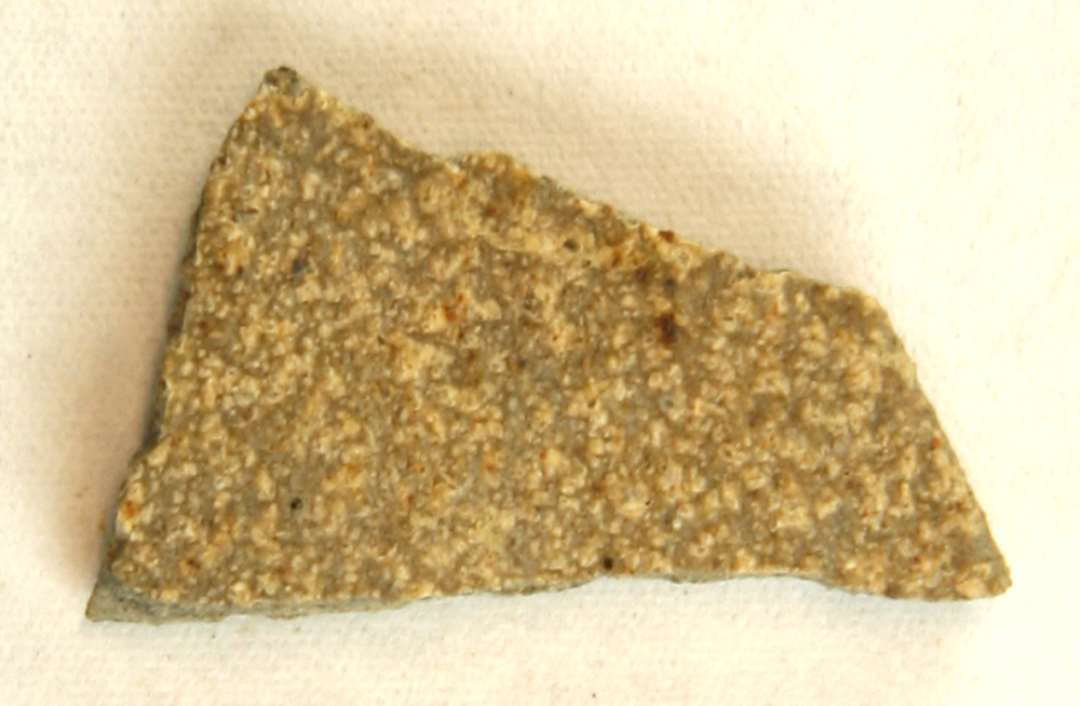 1 ubetydeligt mundingsrandsk�r af gr�brunligt magret stent�j antagelig fra smeltedigel med tresidet munding. Gruppe 2.